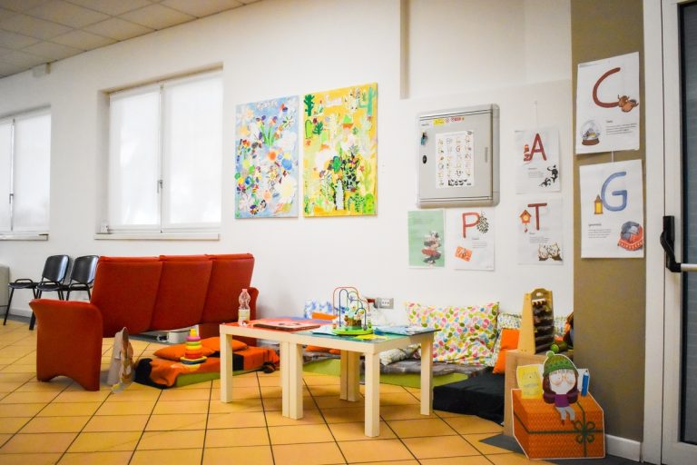 Angolo con divano e tavolino, pareti decorate con disegni colorati
