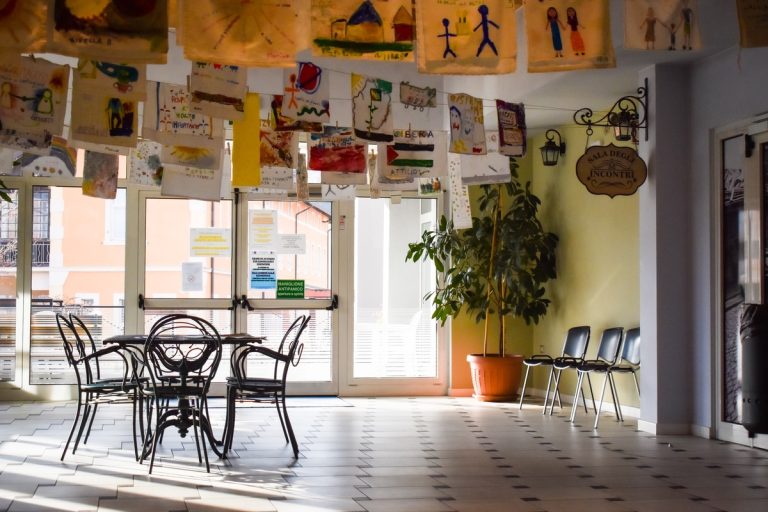 Sala comune con tavolino e sedie, decorata con disegni appesi